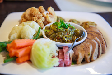 Northern Thai food, Nam Prik Num (Green Chili Dip). Traditional Thai cuisine chili sauce, Thai sausages , deep fried pork skin snack crackling, blanched carrot , cabbage vegetable. Thai food concept