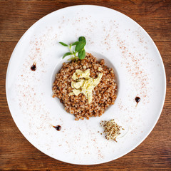 Cooked buckwheat decorated with greenery and pieces of cheese