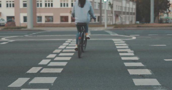 Young woman walking on city streets with bicycle . Gir bike rider crossing pedestrian crossing . 4K video shooting by handheld gimbal