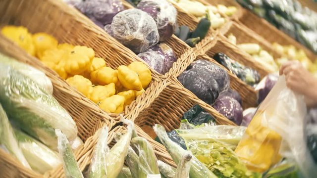 A woman in a supermarket buying vegetables, pumpkin