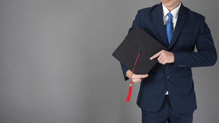 Obraz na płótnie Canvas business man is holding graduation hat, business education concept
