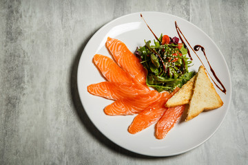 top view on salmon slices served with rucola and tomato salad and toasted bread