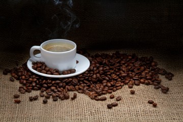 Cup of coffee with coffee beans next to it