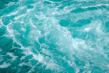 Fototapeta na wymiar Troubled aqua blue sea water with white foam, abstract nature background concept