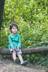 The boy is sitting on a log.