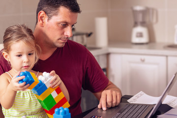 Man working from home and taking care of his daughter..