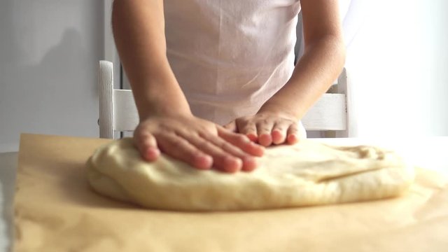 A little girl kneads dough for pizza. The child helps in the preparation of pastry dough 4k video.
