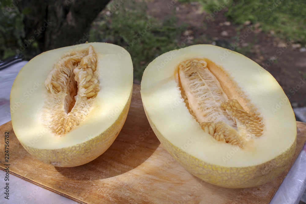 Poster two halves on sweet big tasty melon with seeds on the table