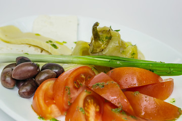 Close-up of fresh summer salad, roasted pepper, tomato, onion, olives and cheese stuffed with dressing, and spices, on a white background. Concept of healthy eating. Shallow depth of focus.