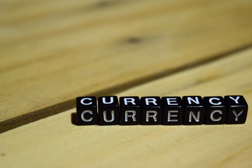 Currency written on wooden blocks. Inspiration and motivation concepts. Cross processed image on Wooden Background