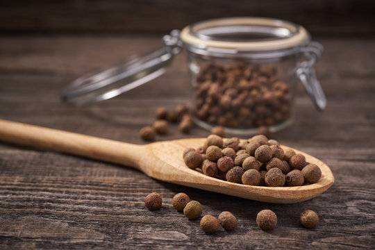 Dried allspice in a wooden spoon close-up