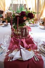 Decorated area in gold and burgundy colors with white candles and flowers, with table number