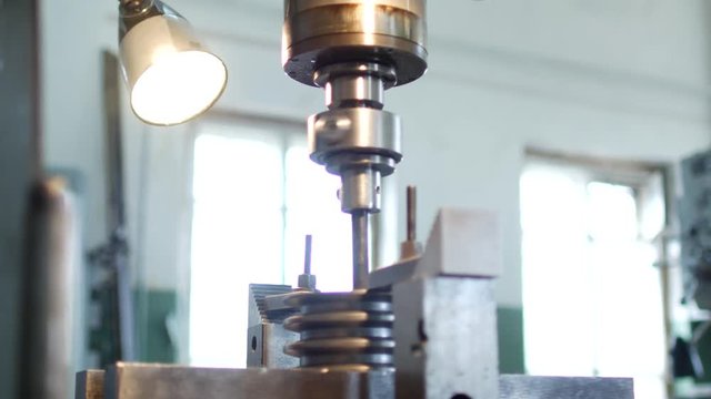 Drilling a hole with a drilling machine in a metal workpiece pulley, close-up, industry, manufacturing pulley, close-up