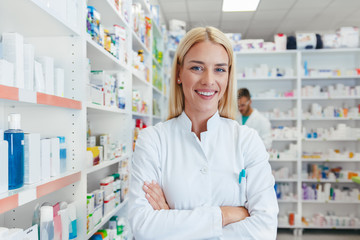 Smiling pharmacist chemist woman standing in pharmacy drugstore, looking at camera