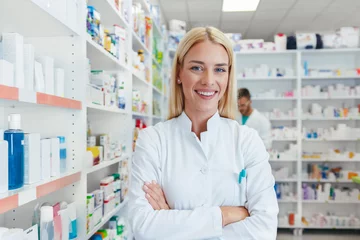 Zelfklevend Fotobehang Glimlachende apotheker-chemicusvrouw die in de apotheek van de apotheek staat en naar de camera kijkt © Karanov images