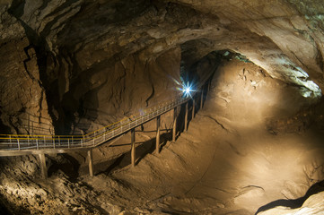 Dark cave view from inside with a lumen. Stalactites and stalagmites inside the stone grotto....