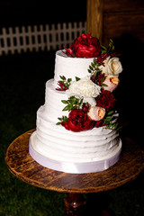 White wedding cake with red and white peonies flowers on it