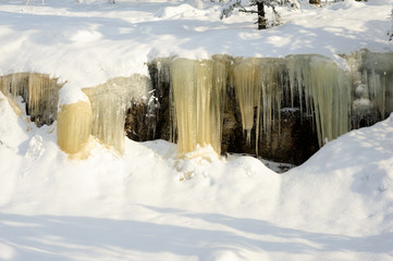 Icicles hanging from a rock cliff. Snowy landscape in Koli National park, Finland