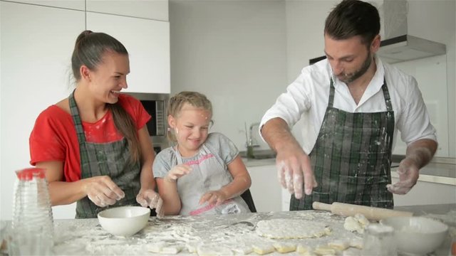 Cute Parents Are Teaching Their Daughter How To Cook Pizza. They Have Good Mood Together.