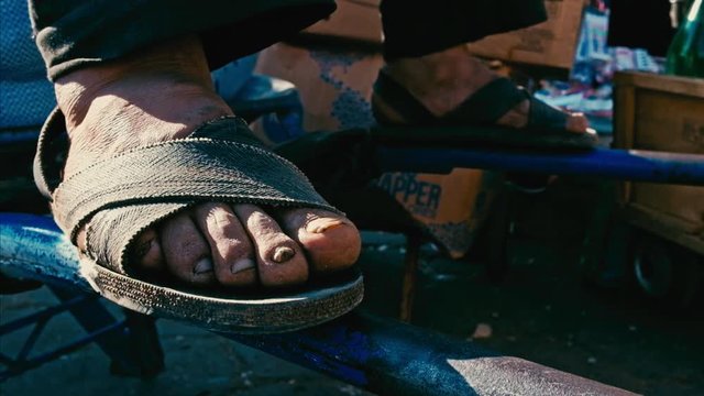 a man feet while resting on his wheelbarrow at the city farmer market