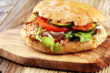 Pulled pork sandwiches with BBQ sauce, cabbage and pickles on wooden table