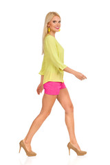Naklejka premium Beautiful Blond Woman In High Heels Is Walking And Smiling