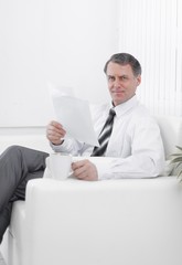 closeup. businessman reading a document while sitting in a chair in the hotel room.