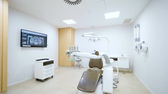 Clean white modern dentist cabinet. Spacious room with a dental radiography on a screen. Cinematic effect with slow motion 