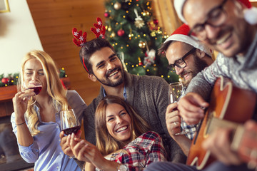 Friends singing Christmas songs and drinking wine