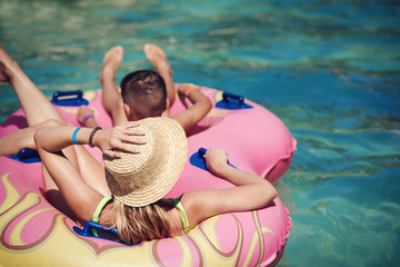Young European lady and her son are enjoying their vacations. They are having fun in water park, swimming in the rubber ring  along the lazy river. - 224767703