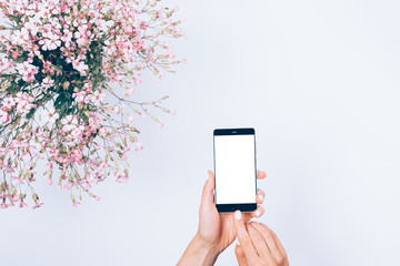 Mobile phone in woman's hands on white table