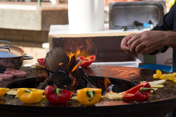 Meat, steaks and sausages with vegetables cooking on grill and smoldering coals. Barbecue