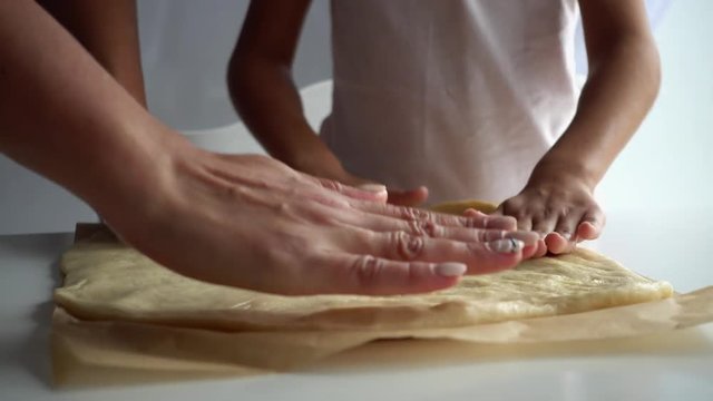 Hands of mother and daughter on a pizza test. The hands of an adult and a child close-up on the test.
