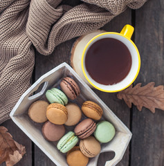 A cup of hot cocoa, macaroons, a knitted sweater on a wooden table. Autumn. Winter. Cozy.