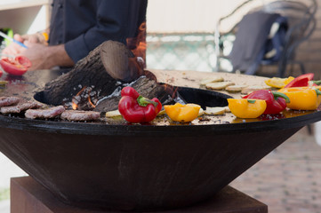 Meat, steaks and sausages with vegetables cooking on grill and smoldering coals. Barbecue