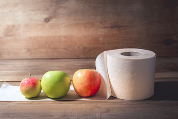 Apples and toilet paper on a wooden background