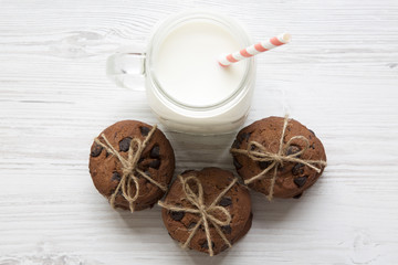Chocolate chip cookies and glass jar of milk on a white wooden background, top view. Close-up.