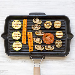 Grilled vegetables in a grilling pan on a white wooden table, overhead view. From above, flat lay, top view.