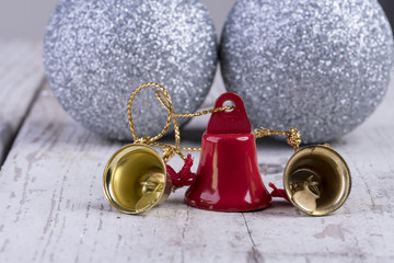 Weihnachtsmotiv mit goldener und roter Glocke auf weißem rustikalen Holz Hintergrund