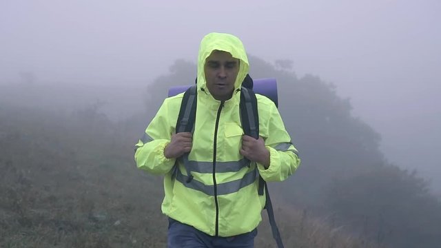 Portrait man tourist with backpack walking alone in the fog