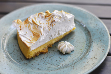 Slice of lemon meringue pie on blue plate.