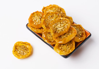 Bowl of dried yellow tomatoes and one piece of tomato on white background