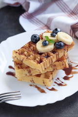 Fresh homemade waffles with blueberries and banana for breakfast on wooden background