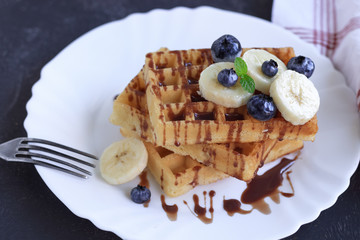 Fresh homemade waffles with blueberries and banana for breakfast on wooden background