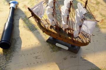 old ship sailboat on an old vintage map, a shameful pipe, the concept of a day of Columbus. Nautical background with a navigation tools: telescope, compass and old maps.