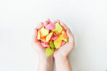 Multicolored origami paper hearts in female hands. Women hands holding many bright heart. Love, romance, dating. Health care, donate and family insurance concept, world heart day, world health day