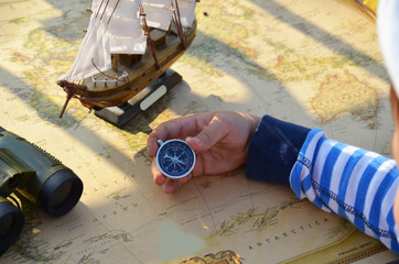 Boy in the image traveler studying his map of travel and adventure in nature. old ship sailboat on...