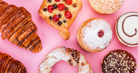 Assortment of sweet cakes and donuts with chocolate cream on pink background, top view