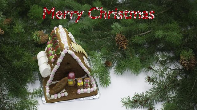 Lebkuchenhaus mit Tannenzweigen und blinkendem Text Merry Christmas