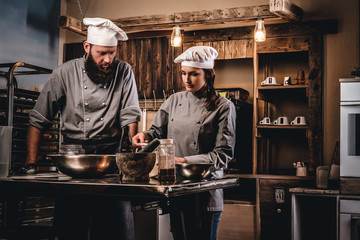 Chef teaching his assistant to bake the bread in the bakery.